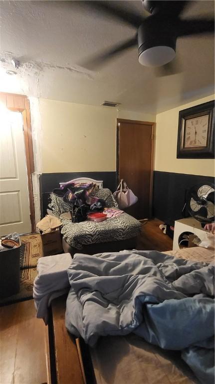 bedroom featuring ceiling fan, visible vents, and wood finished floors