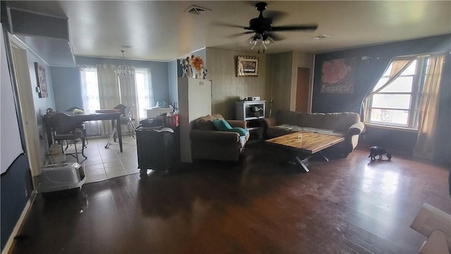 living room with a wealth of natural light, visible vents, wood finished floors, and ceiling fan with notable chandelier