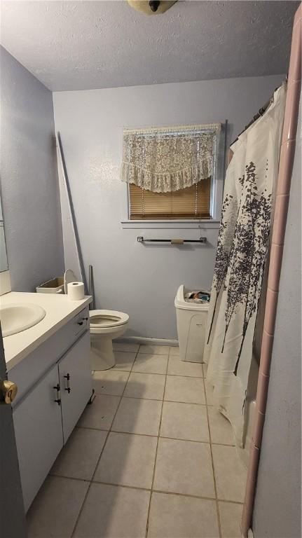 full bath with tile patterned flooring, toilet, vanity, and a textured ceiling