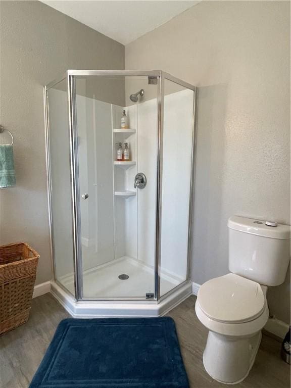 bathroom featuring hardwood / wood-style flooring, vaulted ceiling, an enclosed shower, and toilet