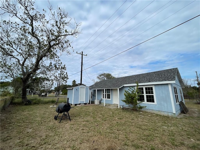 rear view of property with a storage unit and a lawn