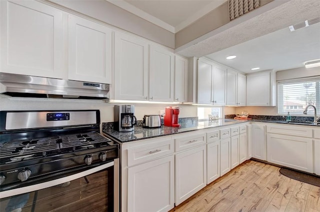 3 Mazatlan Dr, Rockport, TX 78382 - kitchen with gas stove, under cabinet range hood, a sink, light wood finished floors, and white cabinetry