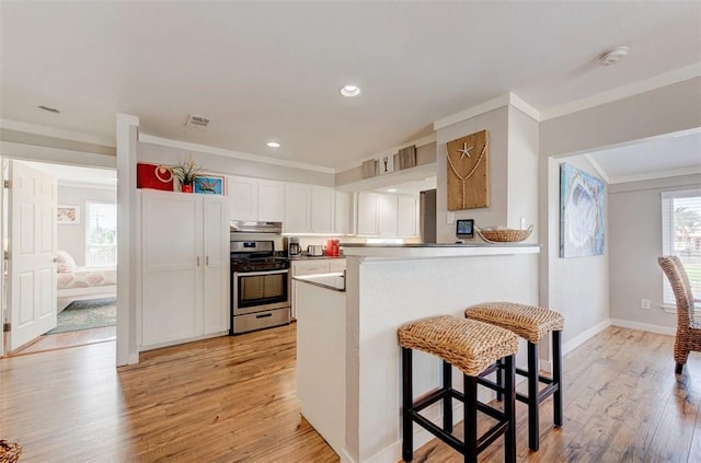 3 Mazatlan Dr, Rockport, TX 78382 - kitchen featuring stainless steel range with gas stovetop, crown molding, under cabinet range hood, white cabinets, and light wood-style flooring