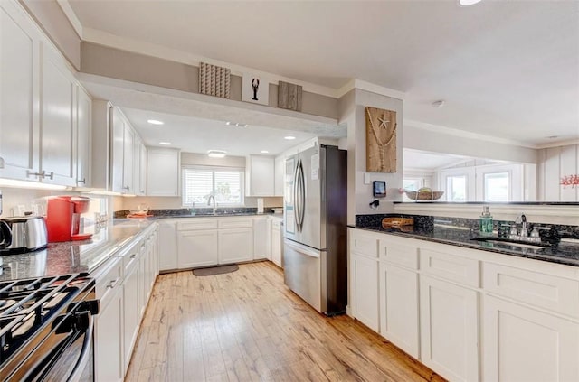 3 Mazatlan Dr, Rockport, TX 78382 - kitchen featuring stainless steel appliances, a sink, white cabinets, light wood-style flooring, and dark stone counters