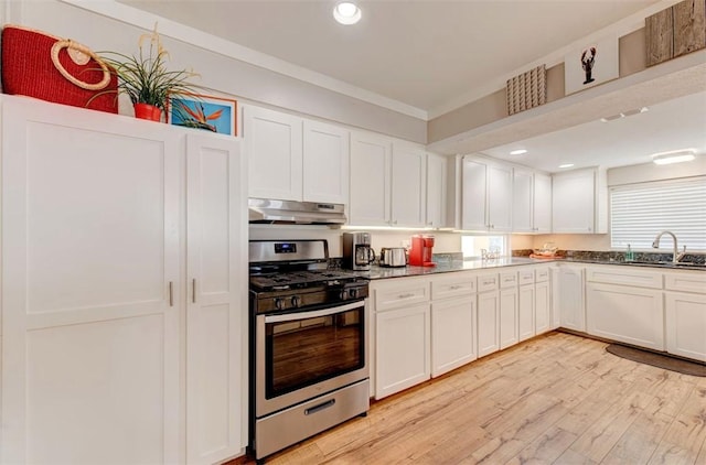 3 Mazatlan Dr, Rockport, TX 78382 - kitchen with stainless steel gas stove, a sink, under cabinet range hood, light wood-style flooring, and white cabinets