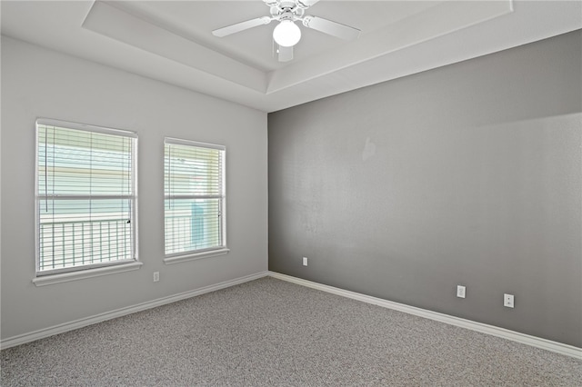 carpeted spare room with ceiling fan and a tray ceiling