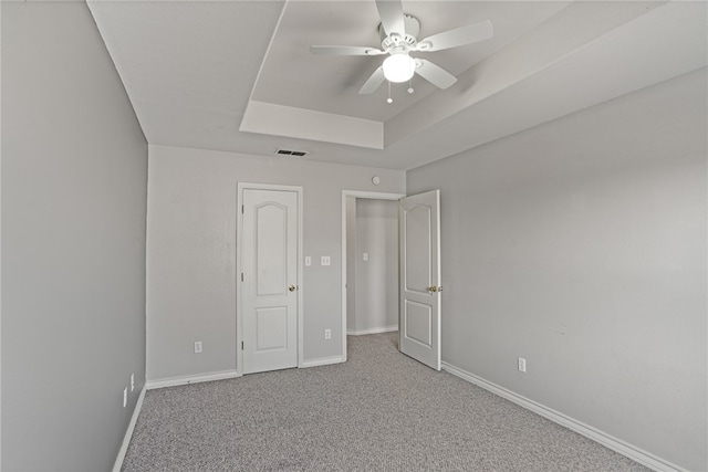 unfurnished bedroom with a tray ceiling, carpet flooring, and ceiling fan