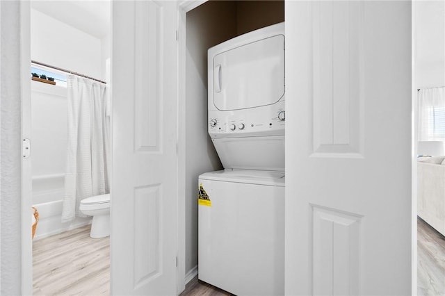 115 N Nautica, Rockport, TX 78382 - laundry room featuring stacked washing machine and dryer, wood finished floors, and healthy amount of natural light