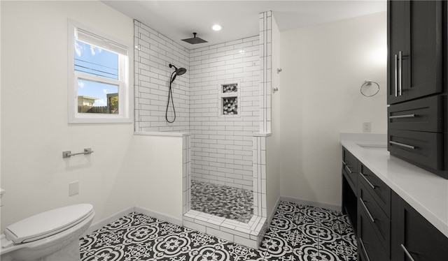 bathroom with toilet, vanity, tile patterned flooring, and a tile shower