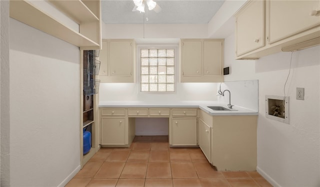 kitchen with light tile patterned flooring, cream cabinetry, a textured ceiling, and sink