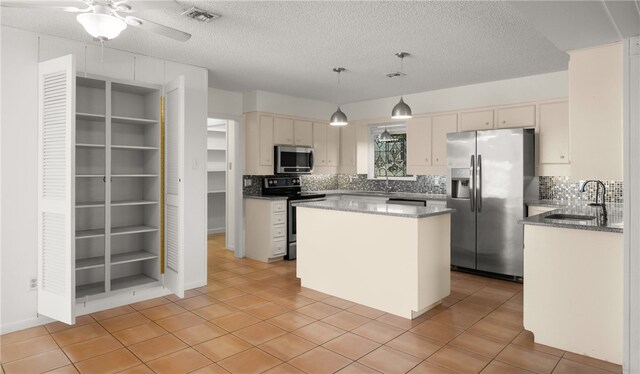 kitchen with stainless steel appliances, sink, a textured ceiling, a center island, and pendant lighting