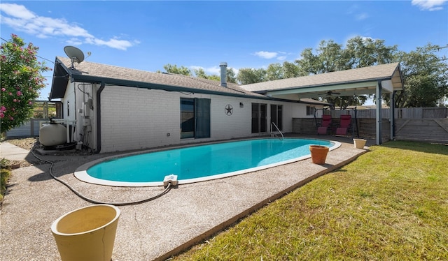 view of swimming pool with a patio, a lawn, and ceiling fan