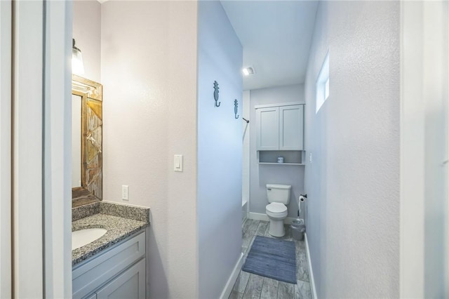 70 Belaire Dr, Rockport, TX 78382 - bathroom featuring vanity, baseboards, wood finished floors, and toilet