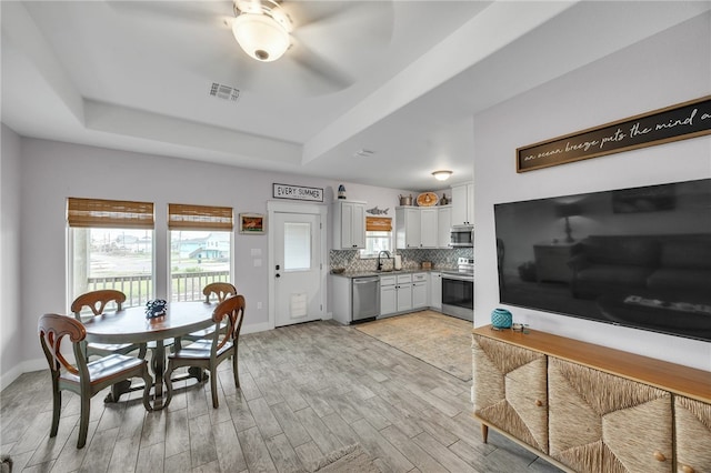 70 Belaire Dr, Rockport, TX 78382 - dining space featuring visible vents, baseboards, light wood-type flooring, a raised ceiling, and a ceiling fan