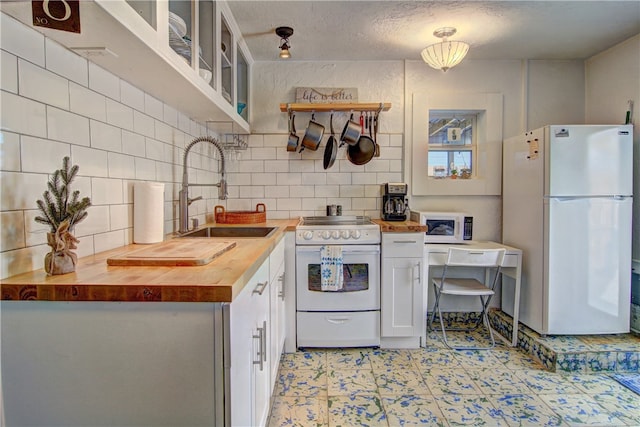 kitchen with sink, a textured ceiling, white appliances, white cabinets, and butcher block countertops