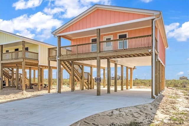 rear view of property featuring a carport, stairway, and driveway