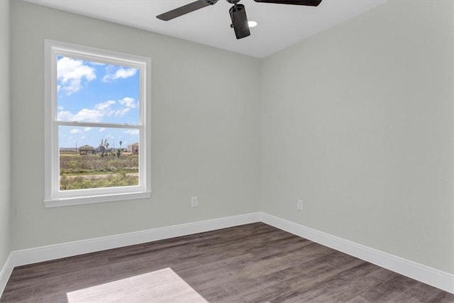 unfurnished room with a ceiling fan, dark wood finished floors, and baseboards