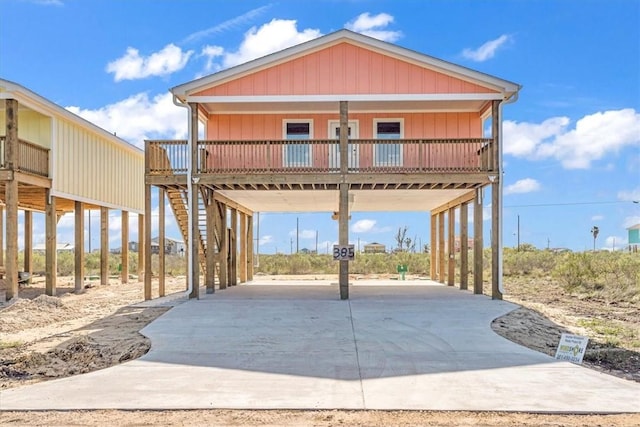 view of front of home featuring driveway, a carport, stairway, and a porch