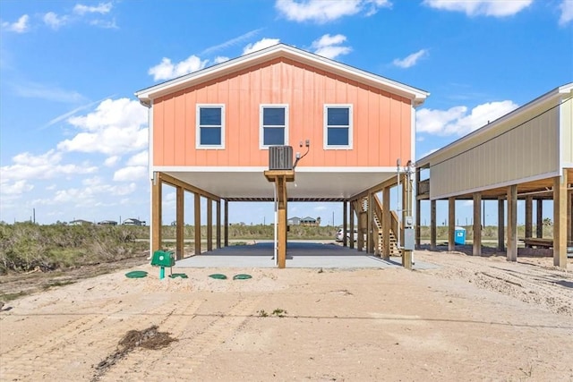 exterior space featuring a carport, board and batten siding, stairs, and concrete driveway