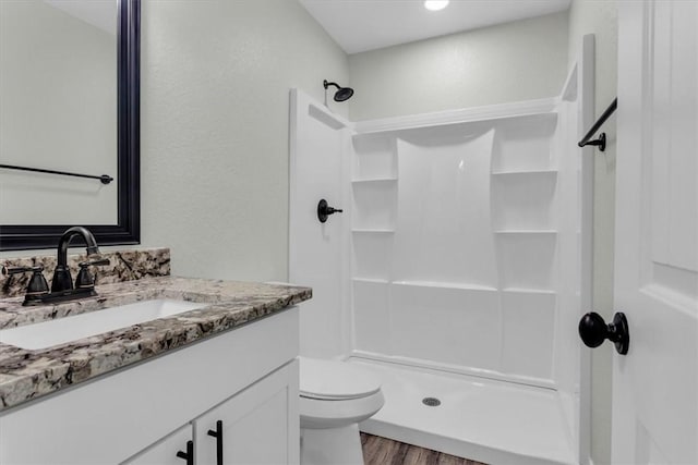 bathroom with toilet, a stall shower, wood finished floors, and vanity