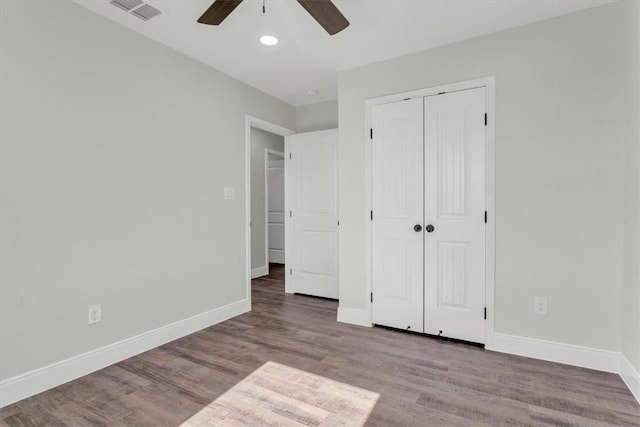 unfurnished bedroom featuring a closet, wood finished floors, visible vents, and baseboards