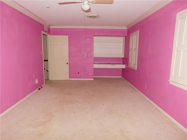 unfurnished room with built in shelves, ceiling fan, carpet flooring, and crown molding