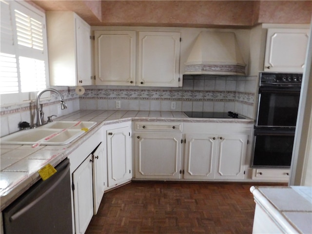 kitchen with tile counters, black appliances, white cabinets, and custom exhaust hood