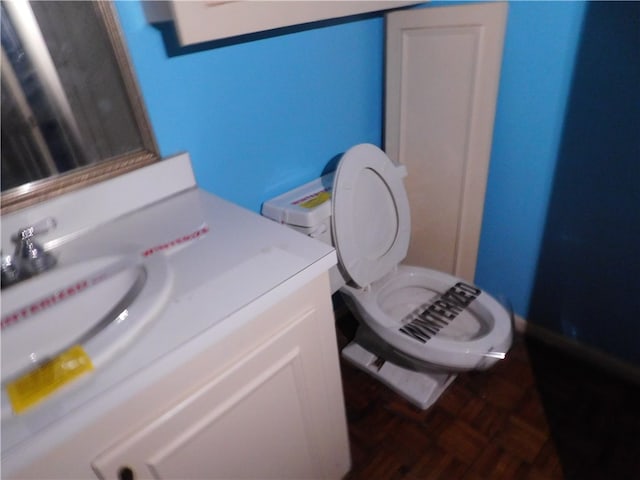 bathroom with vanity, parquet flooring, and toilet