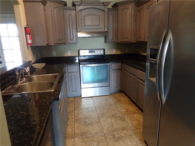 kitchen featuring dark stone countertops, appliances with stainless steel finishes, sink, and light tile patterned floors