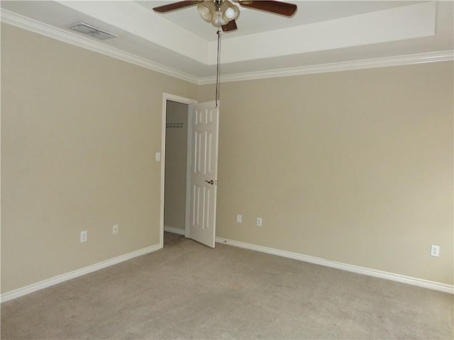 carpeted empty room featuring ceiling fan, ornamental molding, and a tray ceiling