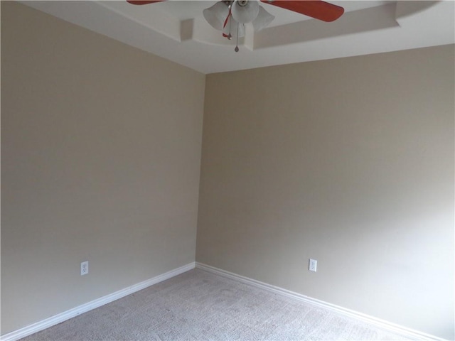 carpeted spare room with ceiling fan and a raised ceiling