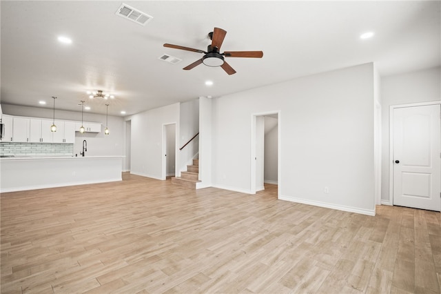 unfurnished living room with recessed lighting, visible vents, light wood-style floors, and stairway