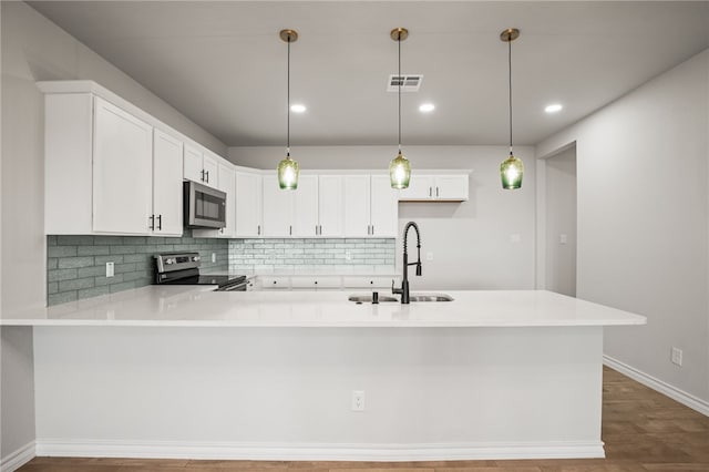 kitchen with visible vents, light countertops, decorative backsplash, appliances with stainless steel finishes, and a sink