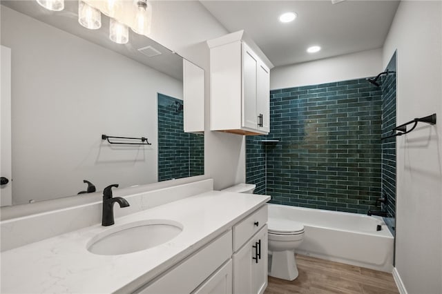 bathroom with vanity, wood finished floors, visible vents, tub / shower combination, and toilet