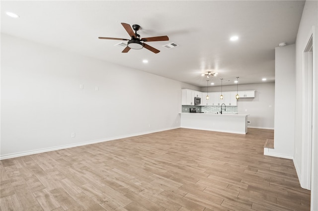 unfurnished living room with visible vents, a sink, recessed lighting, light wood finished floors, and ceiling fan