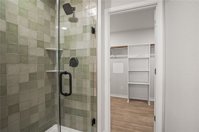 bathroom with wood finished floors, a stall shower, and a spacious closet