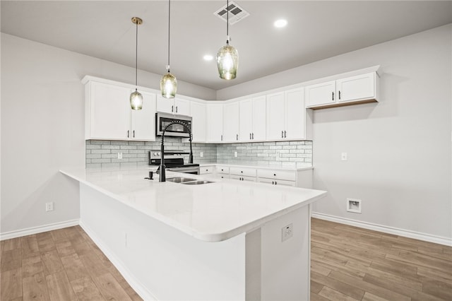 kitchen with visible vents, a sink, stainless steel appliances, a peninsula, and light countertops