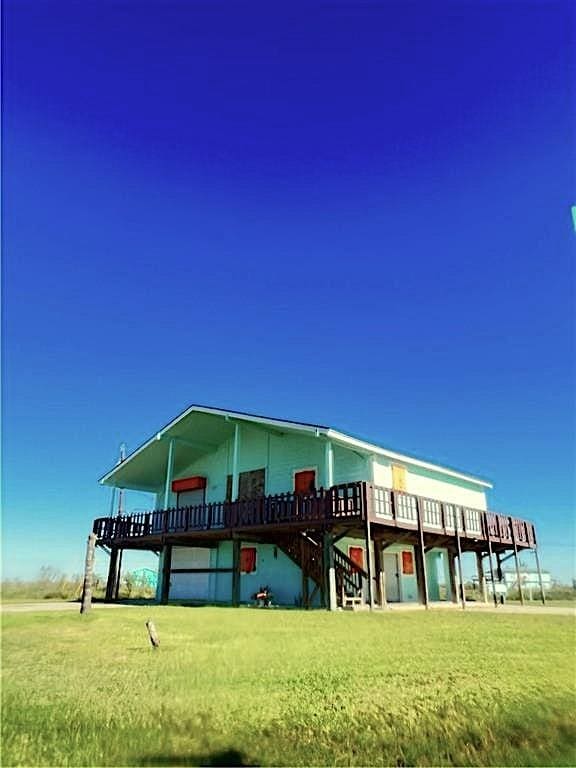 view of front of property featuring stairs, a front lawn, and a wooden deck