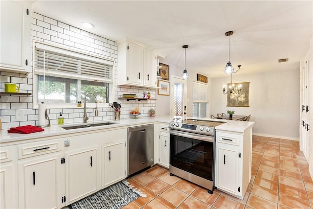 kitchen featuring sink, appliances with stainless steel finishes, white cabinets, decorative light fixtures, and kitchen peninsula