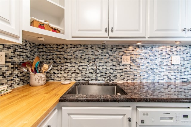 kitchen with butcher block countertops, backsplash, sink, and white cabinets