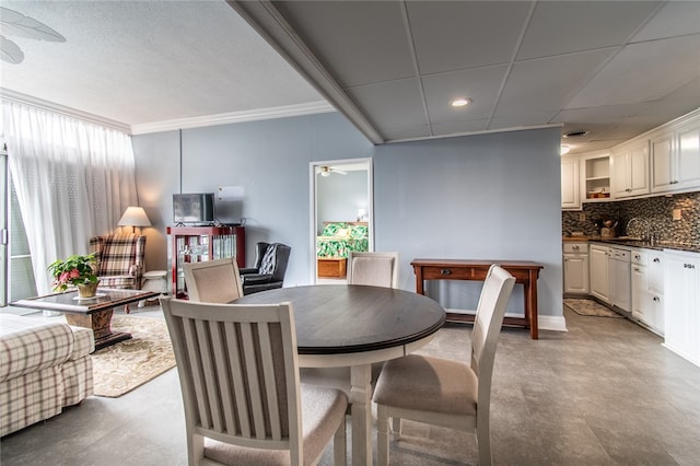 dining space featuring ceiling fan, crown molding, and sink