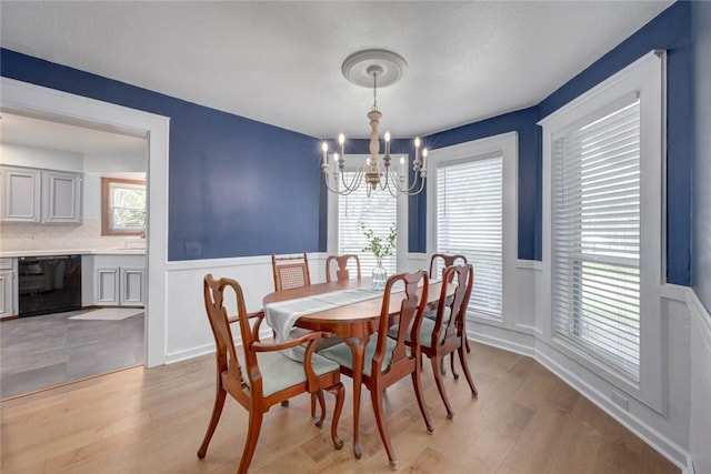 7506 Bistineau Dr, Corpus Christi, TX 78413 - dining area featuring a chandelier, a wainscoted wall, healthy amount of natural light, light wood-style floors, and a decorative wall