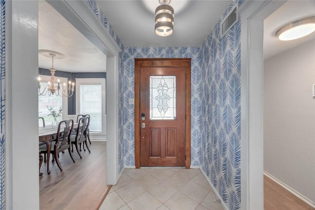 7506 Bistineau Dr, Corpus Christi, TX 78413 - foyer featuring wallpapered walls, a chandelier, an accent wall, and light wood finished floors