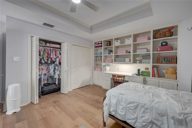 7506 Bistineau Dr, Corpus Christi, TX 78413 - bedroom with a tray ceiling, ornamental molding, light wood-style floors, built in study area, and multiple closets