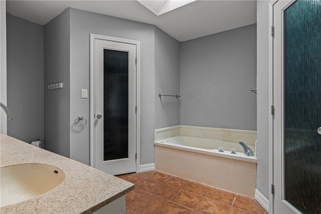 bathroom featuring a skylight, vanity, a bath, and tile patterned floors