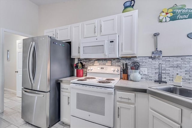 kitchen featuring white appliances, a sink, white cabinetry, light countertops, and tasteful backsplash