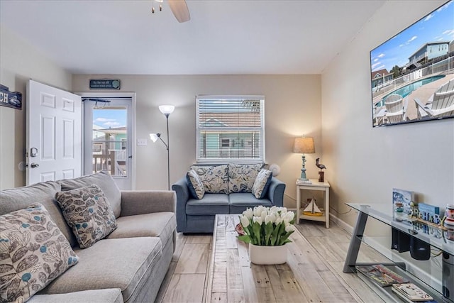 living area featuring light wood-style flooring, baseboards, and a ceiling fan