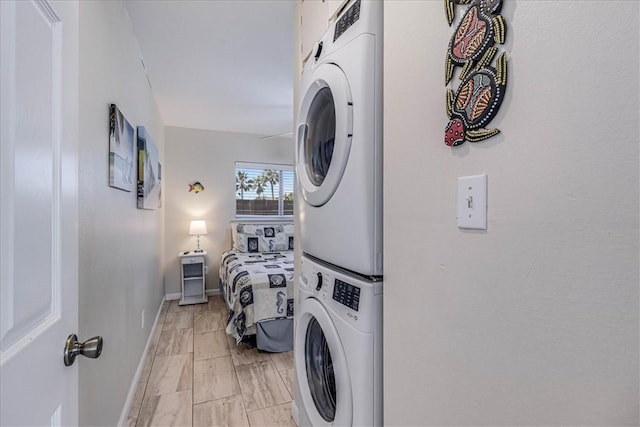 washroom featuring laundry area, baseboards, and stacked washer / dryer