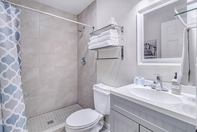 full bathroom featuring tiled shower, vanity, and toilet