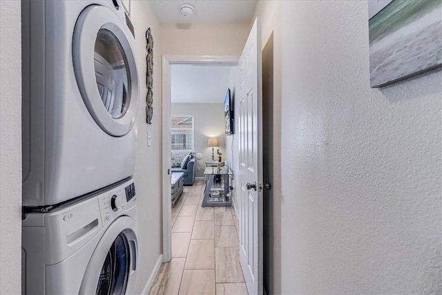 washroom with stacked washer and clothes dryer, light tile patterned flooring, a textured wall, and laundry area